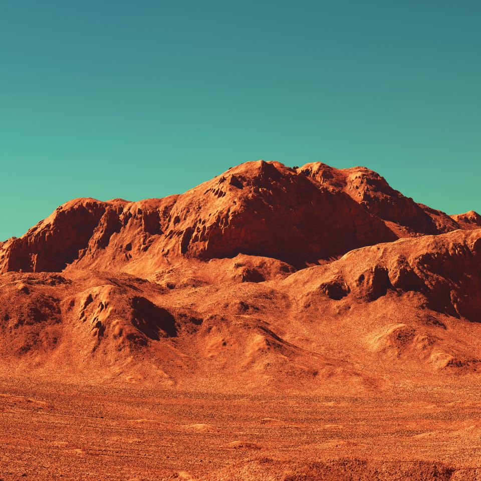 A red martian rocky landscape against a blue-green sky